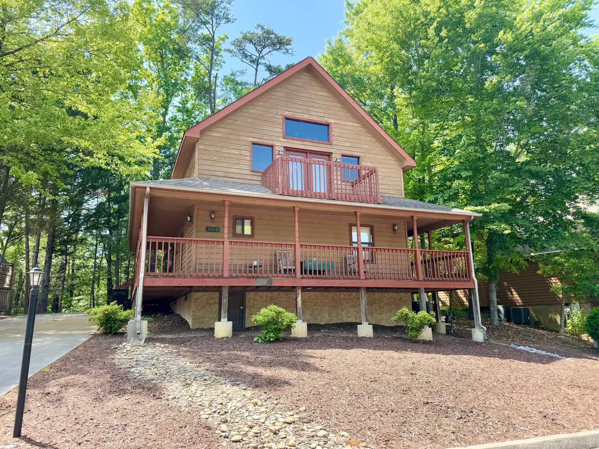 This exterior image showcases a spacious front porch with large windows and lush surrounding greenery. The setting is perfect for family gatherings, with room to enjoy morning coffee or evening sunsets after returning from nearby attractions.