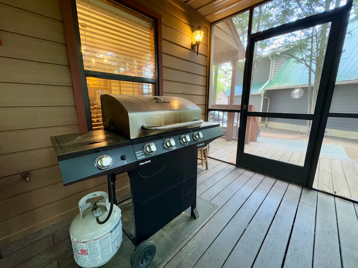 The image showcases a grill set up near a window and lantern, evoking the feel of a designated area for barbecuing and outdoor dining. The relaxed and festive mood makes it ideal for group gatherings and alfresco meals.